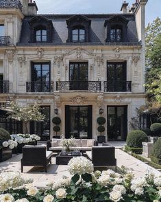 a large building with lots of windows and white flowers in the foreground