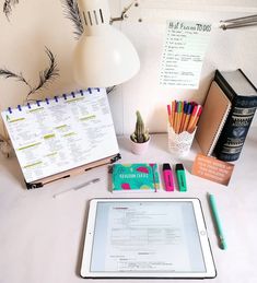 a tablet computer sitting on top of a desk next to a notebook and pen holder