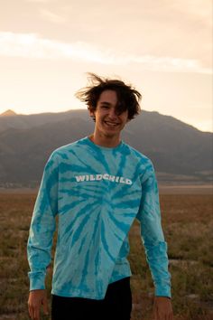 a man standing in the middle of a field wearing a blue tie - dyed shirt