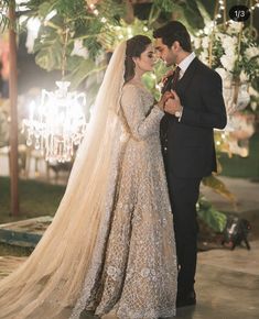 two people standing next to each other in front of a chandelier filled with lights