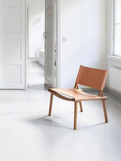 an orange chair sitting in the middle of a white room next to a door and window