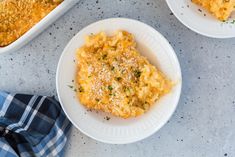 two white plates filled with macaroni and cheese casserole on top of a table