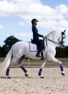 a woman riding on the back of a white horse