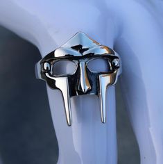 Entfessele den Bösewicht in dir mit dem Silber MF DOOM Ring, der Traum eines jeden Rap-Liebhabers. Dieser silberne Gladiator-Ring ist eine Hommage an die Rap-Legende MF DOOM und seine ikonische Bösewicht-Maske. Das antike Finish und die komplizierten Details auf der Vorderseite des Rings verleihen ihm eine zeitlose und dennoch ausgefallene Anziehungskraft. Sein leichtes Design sorgt für Komfort und verleiht deinem Stil einen Hauch von Geheimnis und Rebellion. Perfekt als Geschenk für die Weihnac Mr Doom Ring, Doom Ring, Mf Doom Ring, Madlib Mf Doom, Gladiator Ring, The Illest Villain Mf Doom, Ring For Men Silver, Villain Mask, Mf Doom Hoodie