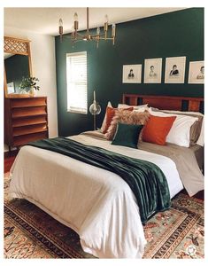 a large bed in a bedroom with green walls and pictures on the wall above it