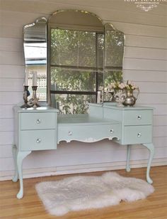 a blue vanity with a mirror and vase on it in front of a white wall