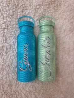 two blue and green water bottles sitting next to each other on a white carpeted floor