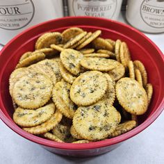 a red bowl filled with crackers next to two bottles