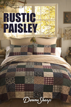 a bed covered in a quilt next to a window with the words rustic paisley on it