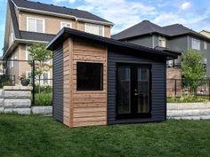 a small wooden shed sitting on top of a lush green field in front of some houses