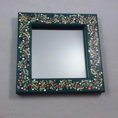 a green frame with red, white and green decorations on it is shown in front of a mirror