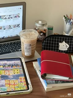 an open laptop computer sitting on top of a wooden desk next to a cup of coffee