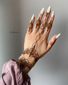 a woman's hand with henna tattoos on it