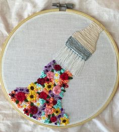 an embroidery project with flowers and a brush in the shape of a dress on a white background