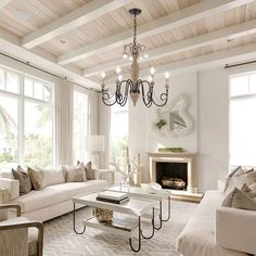 a living room filled with furniture and a chandelier hanging over the fire place