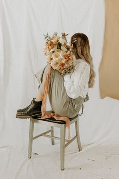 a woman sitting on a chair holding a bouquet of flowers