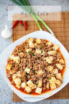 a white plate topped with tofu and rice on top of a table next to chopsticks