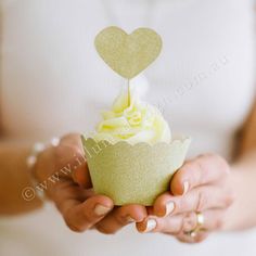 a person holding a cupcake with a heart on top