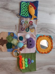 several knitted items are laid out on the floor, including a mirror and toys