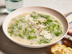 a white bowl filled with soup next to some bread