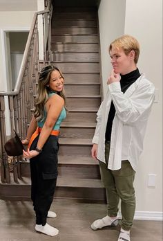 two people standing next to each other in front of stairs