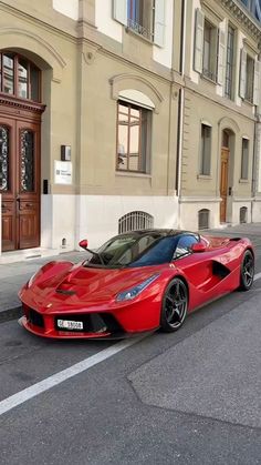 a red sports car is parked on the side of the road in front of a building