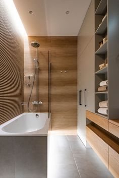 a bathroom with a bathtub, shower and shelving unit in the back wall