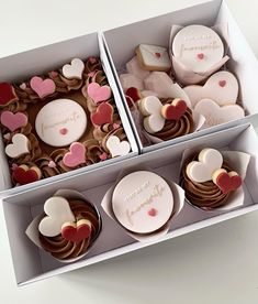 two boxes filled with heart shaped cupcakes on top of a white table next to each other