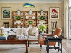 a living room filled with lots of furniture next to a wall mounted bookcase full of vases