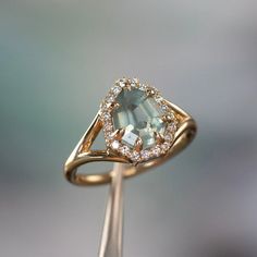 a gold ring with an aquamarine colored stone and diamond halos on the side