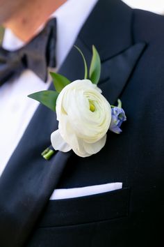 a man in a tuxedo wearing a boutonniere with white flowers