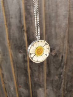 *Beautiful handcrafted real daisy necklace set in resin. *Add some spring sunshine to an outfit *Pendant is resin with a real daisy set inside April birth flower  *Pendant is 28mm x 28mm *Chain is 18 inches and gold plated for gold pendant and silver plated for silver pendant Please let me know if you require a different length chain. *Jewellery care* Please do not shower or sleep with this necklace on and avoid harsh chemicals. Please contact me with any enquiries and thank you for looking at my page Daisy Resin Necklace, White Sterling Silver Birth Flower Necklaces, Dainty White Round Flower Necklace, White Birth Flower Pendant Necklace, Nature-inspired White Birth Flower Necklace, White Flower Charm Necklace, White Flower-shaped Jewelry With Sunflower Design, White Flower Jewelry With Sunflower Design, White Pressed Flowers Necklace For Mother's Day