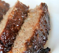 two pieces of meat sitting on top of a white plate covered in jelly and sauce