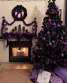 a decorated christmas tree sitting in front of a fire place with purple decorations on it