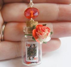 a tiny glass bottle with a rose and card on the top is being held by someone's hand