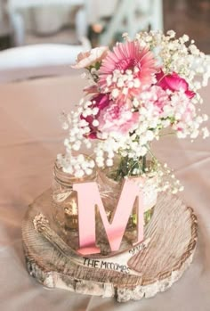 a vase filled with flowers sitting on top of a wooden table next to the letter m