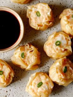 some dumplings are sitting on a plate next to a dipping sauce