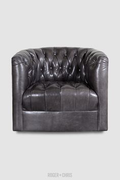 a grey leather chair with buttons on the back and arms, sitting in front of a gray background