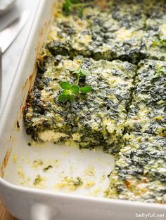 spinach and cheese casserole in a white dish with silverware on the side