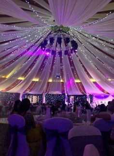 the inside of a large tent with white draping and purple lights on it