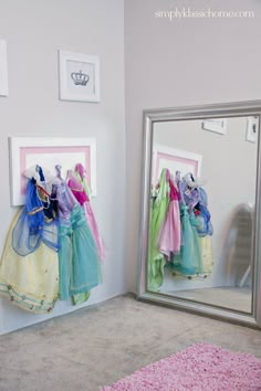 two mirrors with clothes hanging on them in front of a pink and blue carpeted floor