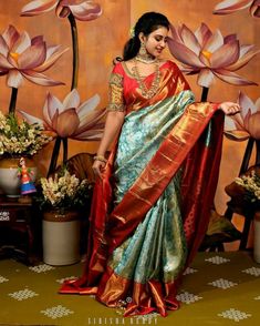 a woman in a red and blue sari with flowers on the wall behind her