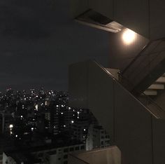 a view of the city at night from a high rise building with stairs leading up to it