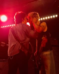 two men standing on stage with one holding a guitar