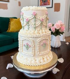 a three tiered white cake sitting on top of a table next to a green couch