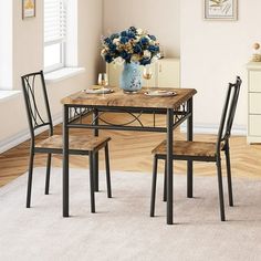 a dining room table with two chairs and a vase filled with flowers