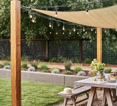 an outdoor dining area with table, bench and string lights