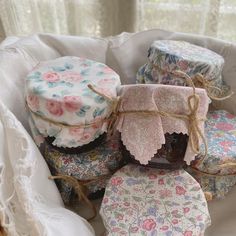 small round boxes with floral designs are in a basket