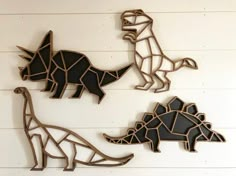 three metal dinosaurs on a white wall with wood planks in the shape of geometric shapes