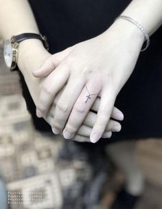 two hands holding each other with a cross tattoo on them